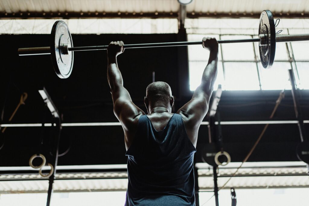 Man lifting barbell in gym from back view highlighting strength and fitness.